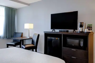 a hotel room with a bed and a television and a table at Days Inn by Wyndham Victoria Airport Sidney in Sidney