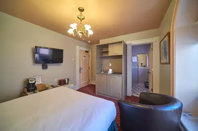 a bedroom with a large white bed and a kitchen at The Bedford Regency Hotel in Victoria