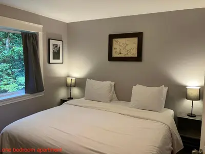 a bedroom with a bed with white sheets and a window at Sienna's Tree House (Tall Trees And Salty Breeze) in Tofino
