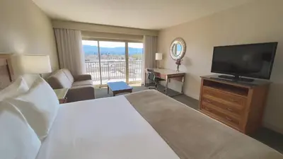 a hotel room with a bed and a flat screen tv at Coast Capri Hotel in Kelowna
