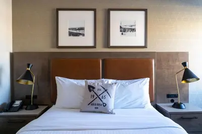 a bedroom with a bed with white sheets and two lamps at Best Western Gold Rush Inn in Whitehorse