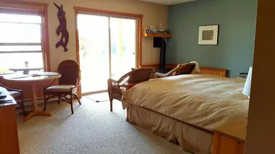 a bedroom with a bed and a table and a window at Reef Point Oceanfront Bed and Breakfast in Ucluelet