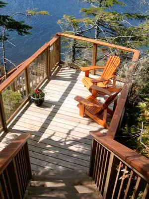 a wooden deck with a bench and a pot of flowers at Reef Point Oceanfront Bed and Breakfast in Ucluelet