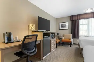 a hotel room with a bed and a desk with a television at Best Western Plus Country Meadows Inn in Aldergrove
