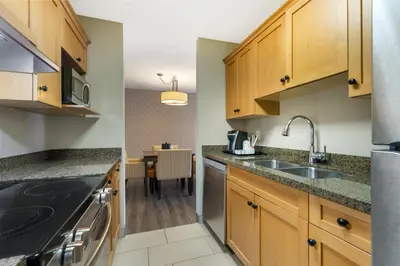 a kitchen with wooden cabinets and a sink and a table at Best Western Plus Country Meadows Inn in Aldergrove