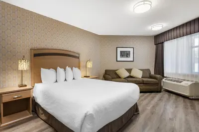 a hotel room with a large bed and a couch at Best Western Plus Country Meadows Inn in Aldergrove