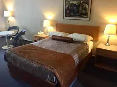 a hotel room with a bed with two tables and two lamps at Avalon Inn in Osoyoos