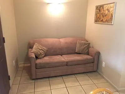 a brown couch in a corner of a room at Avalon Inn in Osoyoos
