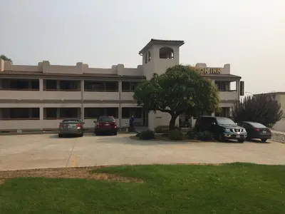 a building with cars parked in a parking lot at Avalon Inn in Osoyoos