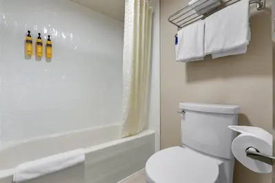 a bathroom with a white toilet and a bath tub at Best Western PLUS Burnaby Hotel in Burnaby
