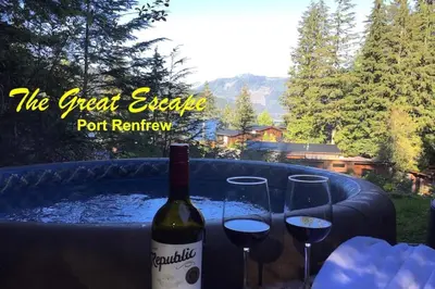 a bottle of wine and two wine glasses on a table at The Great Escape - Port Renfrew in Port Renfrew