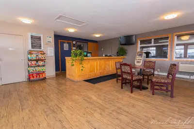 a restaurant with a table and chairs and a refrigerator at Empire Inn & Suites in Red Deer