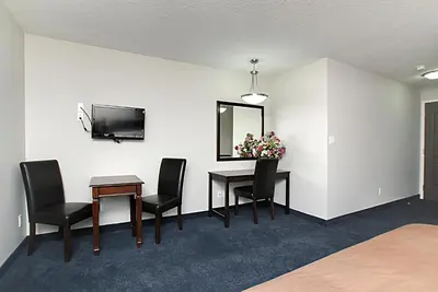 a room with a table and chairs and a television at Travelodge by Wyndham Wetaskiwin in Wetaskiwin