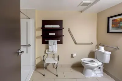 a bathroom with a toilet and a chair at Best Western Plus Edmonton Airport Hotel in Leduc