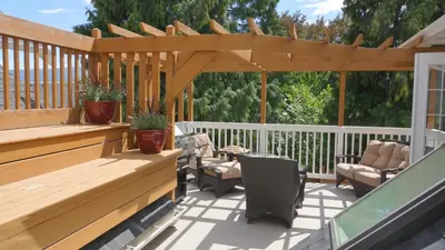 a deck with a wooden pergola and chairs at CHATHAM HOUSE Kelowna Bed & Breakfast in Kelowna