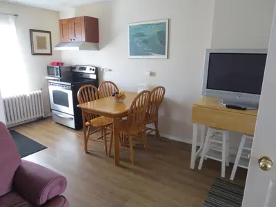 a living room with a table and a kitchen with a television at Burns Lake Bed and Breakfast in Burns Lake