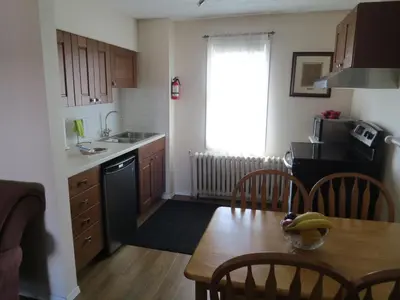a kitchen with a wooden table and a kitchen with a sink and a stove at Burns Lake Bed and Breakfast in Burns Lake