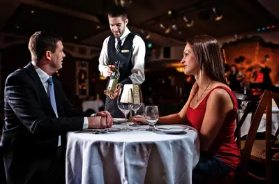 a man and a woman sitting at a table with a waiter at Harrison Hot Springs Resort & Spa in Harrison Hot Springs