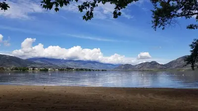 a view of a lake with mountains in the background at Sandy Beach Suites in Osoyoos