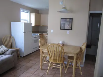 a kitchen with a table and chairs and a white refrigerator at Sandy Beach Suites in Osoyoos
