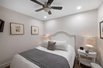 a white bedroom with a bed and a ceiling fan at Ocean Trails Resort in Parksville