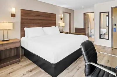 a bedroom with a large bed and a chair at Best Western Maple Ridge in Maple Ridge District Municipality