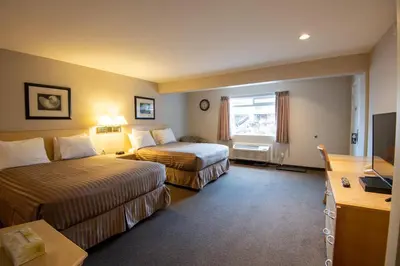 a hotel room with two beds and a television at Canadas Best Value Inn-Prince George in Prince George