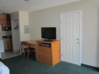 a room with a television on a dresser with a desk at Ramada Merritt in Merritt