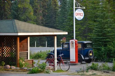 an old car parked next to a gas station at Johnston Canyon Lodge & Bungalows in Castle Junction