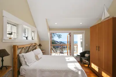 a bedroom with a bed and a sliding glass door at Black Rock Beach House in Ucluelet