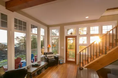 a living room with a staircase and large windows at Black Rock Beach House in Ucluelet