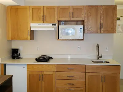 a kitchen with wooden cabinets and a microwave at Sun Peaks Lodge in Sun Peaks