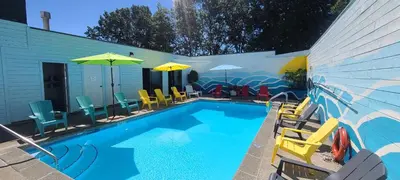a swimming pool with colorful chairs and umbrellas at The Cedars Inn Hotel & Convention Centre in Gibsons