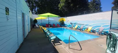 a swimming pool with chairs and umbrellas next to a building at The Cedars Inn Hotel & Convention Centre in Gibsons