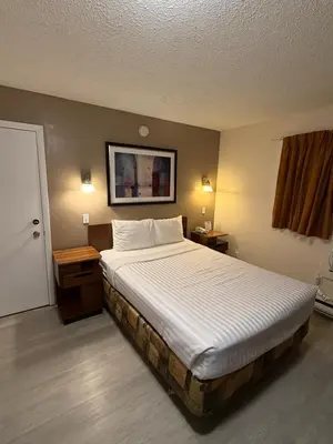 a bedroom with a large bed and two night stands at Canadas Best Value Inn Kelowna in Kelowna