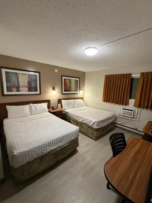 a hotel room with two beds and a table at Canadas Best Value Inn Kelowna in Kelowna