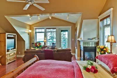 a living room with a bed and a fireplace at Bonniebrook Lodge in Gibsons