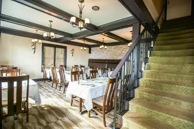 a dining room with a table and chairs and stairs at Bonniebrook Lodge in Gibsons