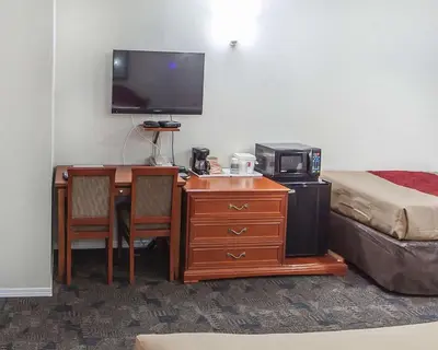 a room with a desk with a television and a bed at Econo Lodge Inn & Suites Drumheller in Drumheller