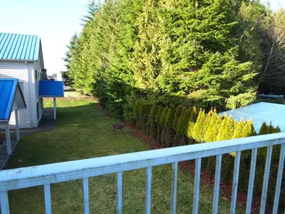 a deer standing in the yard next to a fence at Whale's Tail Guest Suites in Ucluelet