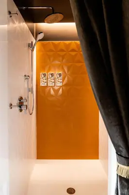 a bathroom with a shower with an orange wall at Hotel Zed Tofino in Tofino