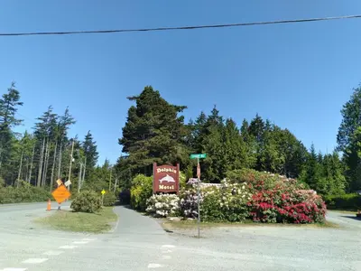 a sign on the side of a road with flowers at Dolphin Motel in Tofino