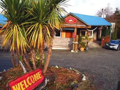 a welcome sign in front of a store with two palm trees at West Coast Motel on the Harbour in Ucluelet