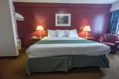 a hotel room with a large bed and two chairs at Port Augusta Inn in Comox