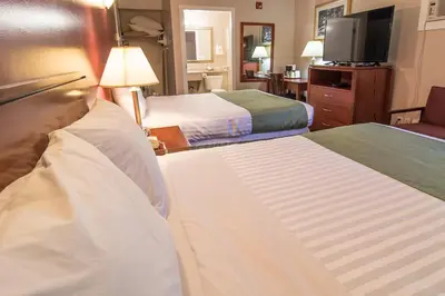 a hotel room with two beds and a flat screen tv at Port Augusta Inn in Comox