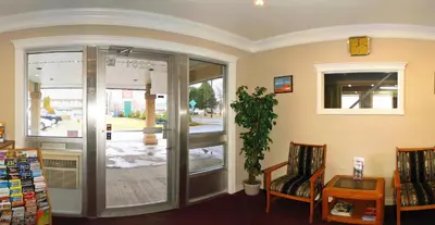 a waiting room with a glass door and a chair at Travelodge by Wyndham Merritt in Merritt