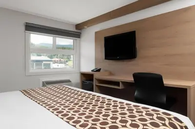 a bedroom with a bed and a desk and a television at Travelodge by Wyndham Blairmore in Blairmore