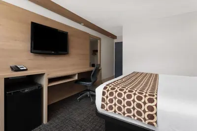 a hotel room with a bed and a desk with a tv at Travelodge by Wyndham Blairmore in Blairmore