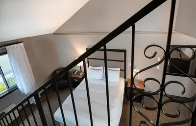 a bedroom with a bed with white sheets and a railing at Prestige Vernon Hotel in Vernon