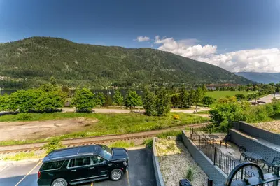 a black suv parked in a parking lot in front of a mountain at Prestige Inn Nelson in Nelson